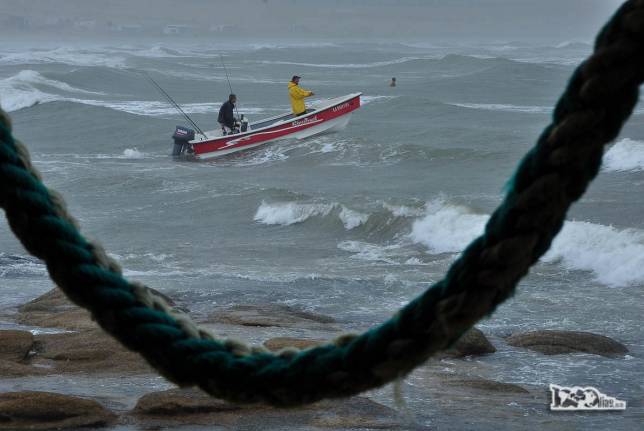 Barco sai na chuva e com mar agitado em Cabo Polonio, no litoral do Uruguai